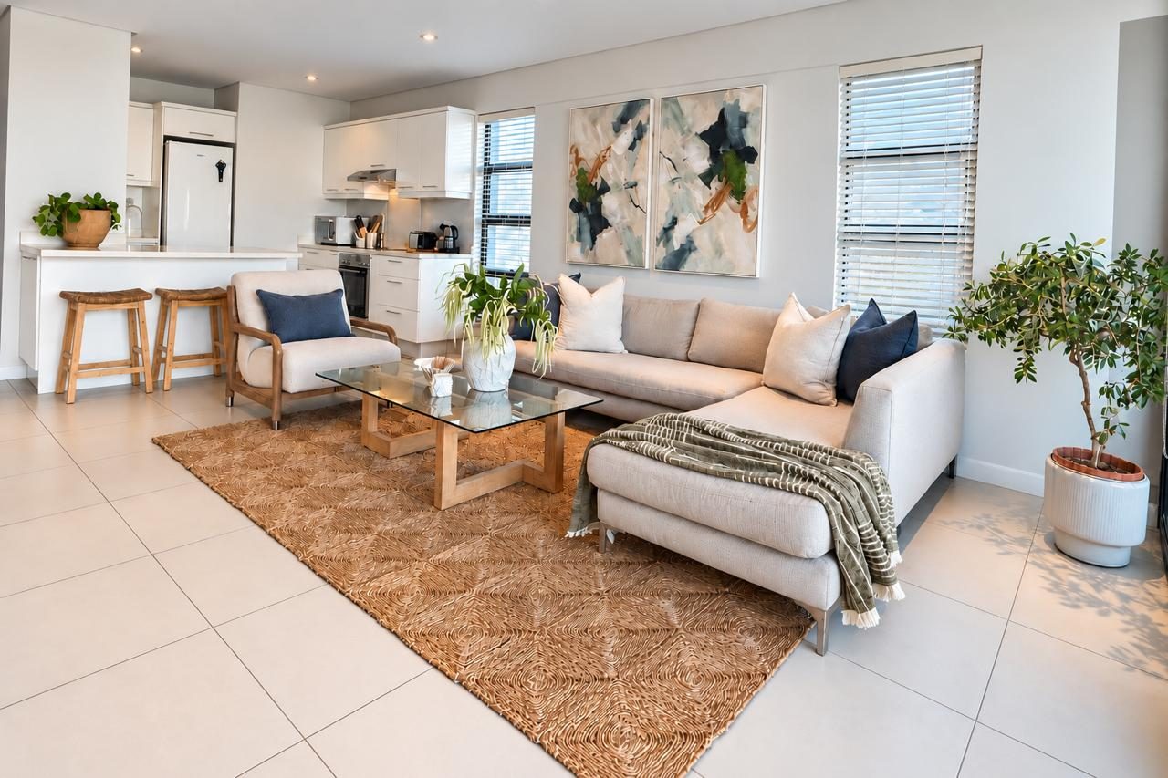 Lounge with jute rug, abstract art and open-plan kitchen